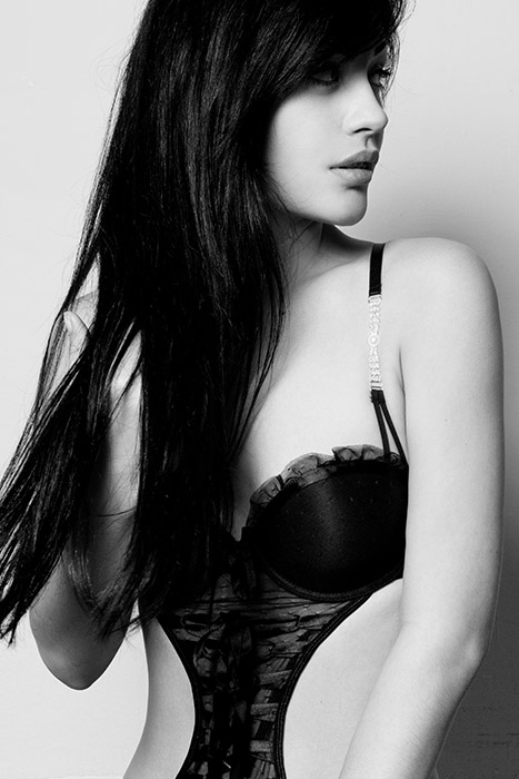 Zwart-wit boudoirportret in zijaanzicht, zacht studiolicht en elegante lijnen.